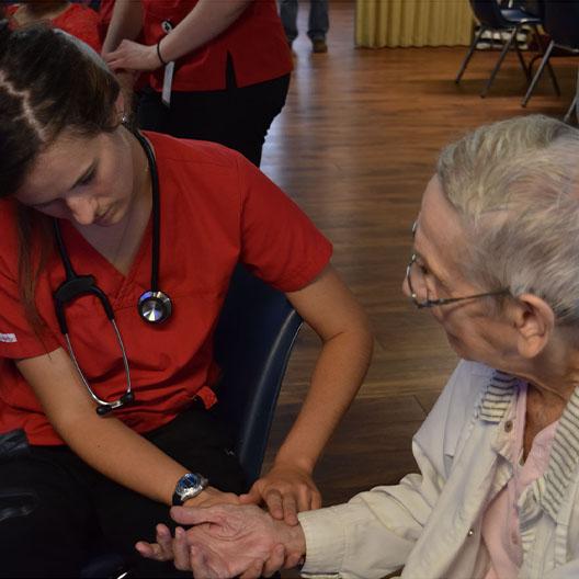 Nursing student taking pulse of an elderly patient